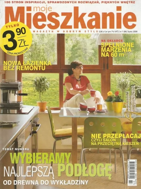 Kobieta siedząca przy stole w jasnej kuchni z widokiem na zieleń – okładka magazynu wnętrzarskiego