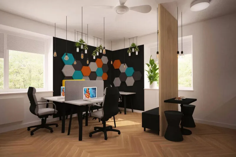 Biuro z szaro-czarnymi boksami do pracy i trzema szarymi, wygodnymi fotelami biurowymi. Podłoga jasna, drewniana. Drewniana ścianka działowa oddzielającą cześć socjalną z czarnym stołem i dwoma czarnymi taboretami. W biurze są cztery duże okna z widokiem na ogród.