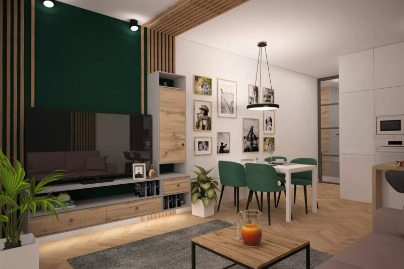 Duzy pokój w kolorze biało-zielonym. Duży telewizor, biały stół z czterema zielonymi krzesłami. Na środku szary dywan i mały drewniany stoliczek.