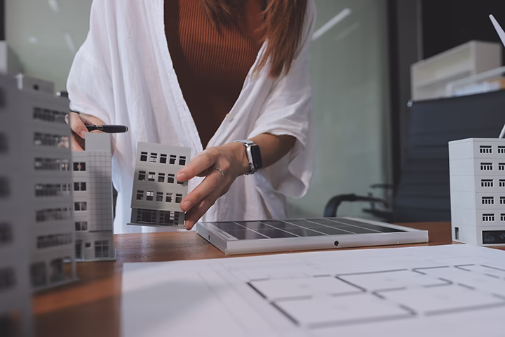 Architekt pracujący nad makietą budynku i planem funkcjonalnym wnętrza.