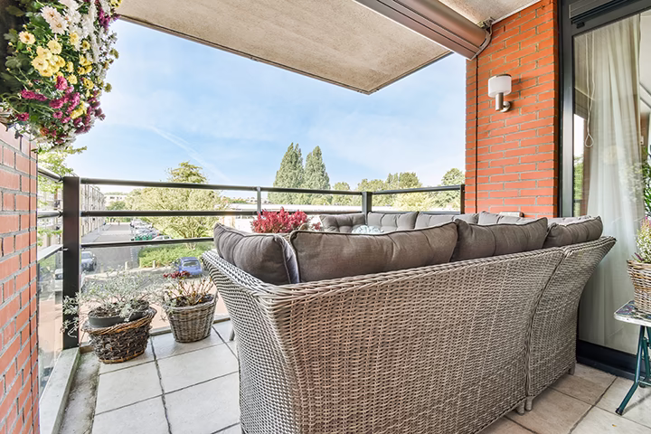 Nowoczesny balkon z dużą szarą kanapą i ceglaną ścianą.