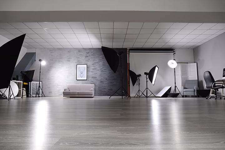 Nowoczesne studio projektowe z profesjonalnym oświetleniem i szarą kanapą.