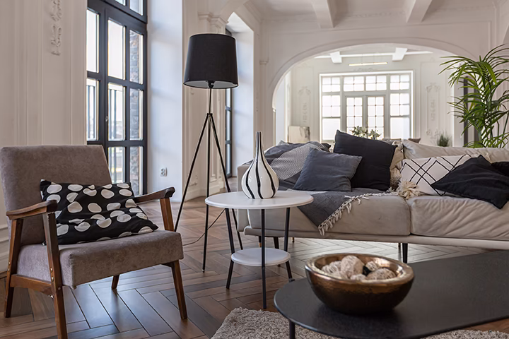 Nowoczesny salon w stylu loft z dużymi oknami i stylowymi meblami.