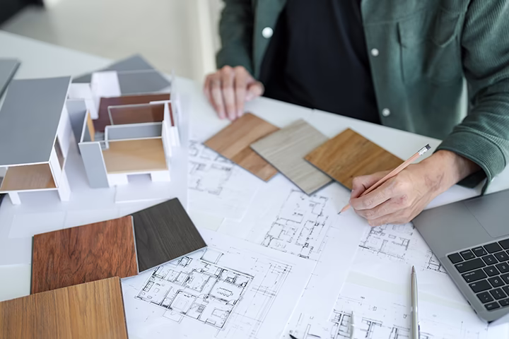 Architekt projektujący wnętrze przy użyciu rzutów i próbek materiałów.