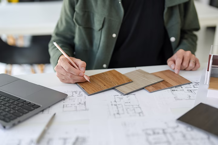 Projektant wnętrz dobierający próbki podłóg do planu architektonicznego.