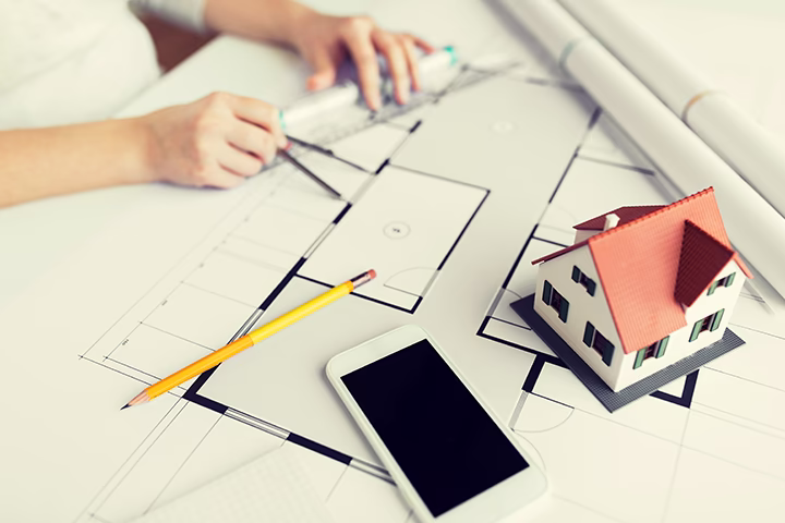 Architekt pracujący nad planem technicznym wnętrza z makietą domu