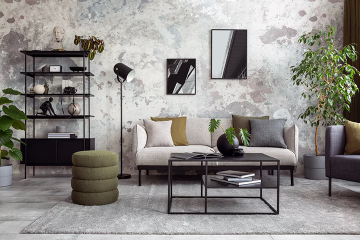Nowoczesny salon z szarą sofą, czarnym stolikiem i betonową ścianą
