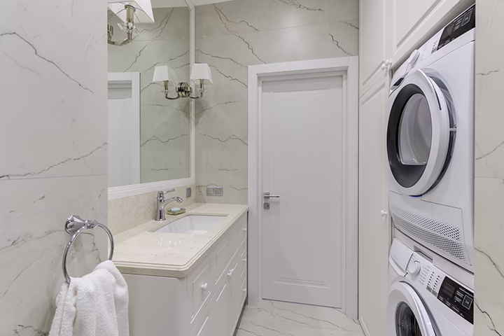 Nowoczesna łazienka, białe meble, pralka, suszarka, płytki marmurowe, projekt wnętrz.