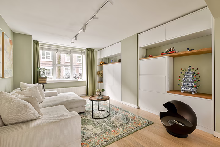 Jasny salon z zielonymi ścianami i białą zabudową meblową