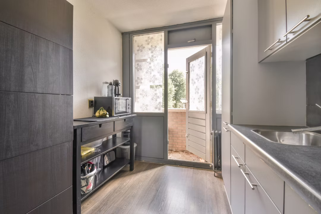 Wąska kuchnia z szarymi meblami i wyjściem na balkon
