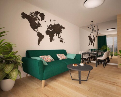 Inspirująca przestrzeń do pracy – gabinet na poddaszu z motywem podróżniczym. Domowe biuro na poddaszu z zieloną sofą i czarną naklejką na ścianie w kształcie mapy świata.