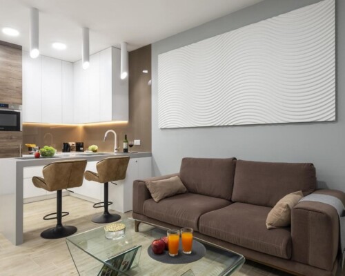 Komfortowy salon z kuchnią i elegancką dekoracją na ścianie Wnętrze salonu z kuchnią i ozdobną falistą dekoracją ścienną
