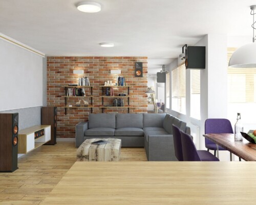 Stylowy salon z elementami industrialnymi i strefą jadalnianą – przestronna aranżacja wnętrza Salon z ceglaną ścianą, szarą sofą narożną i jadalnią z drewnianym stołem – nowoczesne wnętrze