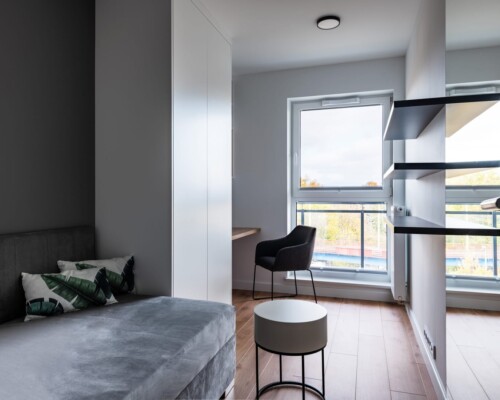 Jasna sypialnia – prostota i komfort Sypialnia z dużym oknem, wyjściem na balkon i nowoczesnym wystrojem