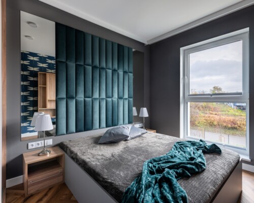 Kącik relaksu – miękkość, światło i spokój Strefa wypoczynku przy oknie z granatową kotarą, półkami i dekoracyjną narzutą