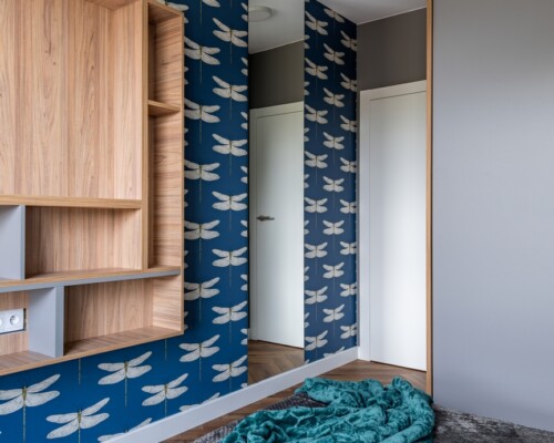 Kolorowy akcent w przedpokoju – styl i wygoda Przedpokój z niebieską tapetą w jodełkę, zabudową meblową i miękkim siedziskiem
