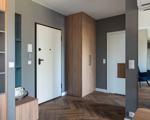 Stylowy przedpokój – elegancja już od wejścia Przedpokój z drewnianą jodełką, szafą wnękową i siedziskiem – projekt mieszkania