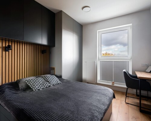 Funkcjonalna sypialnia – każdy centymetr w użyciu Sypialnia z zabudową meblową wokół łóżka, biurkiem i tapicerowanym zagłówkiem